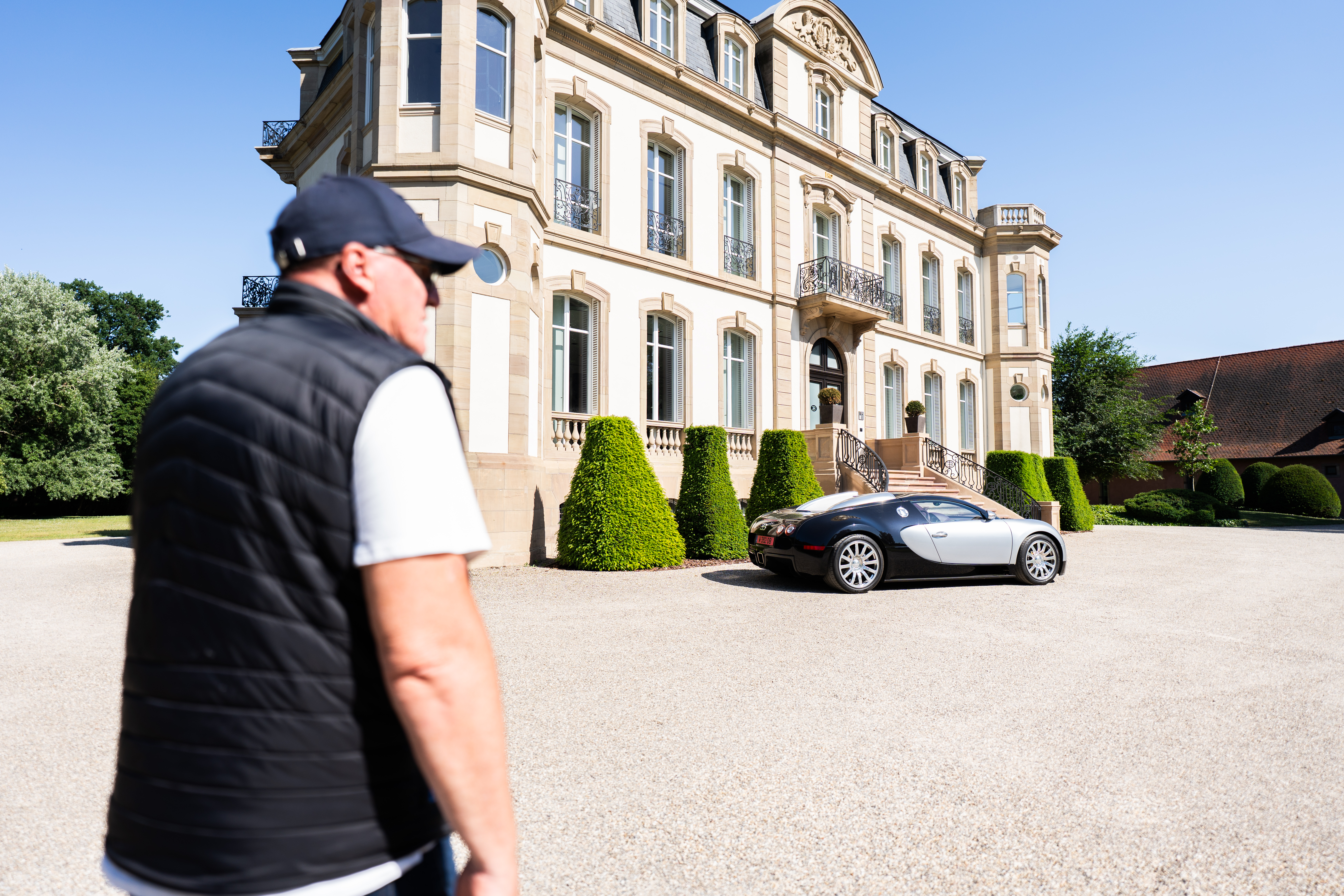 Patrick Burk walks through the courtyard of Château Saint Jean alongside the Bugatti Veyron.